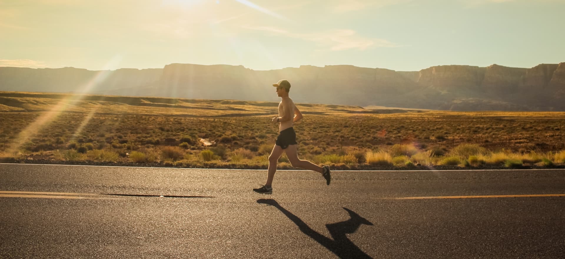 A runner on an open road at golden hour